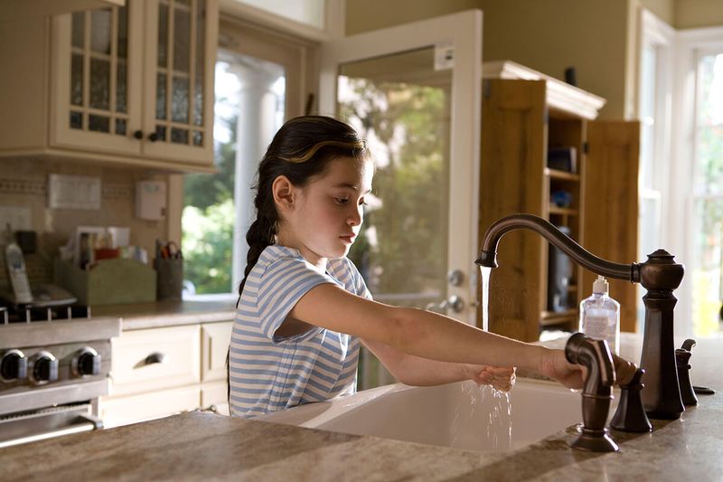Girl Washing Hands at Kitchen Faucet