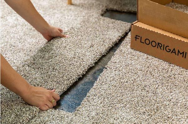 Person installing floorigami peel and stick carpet tiles